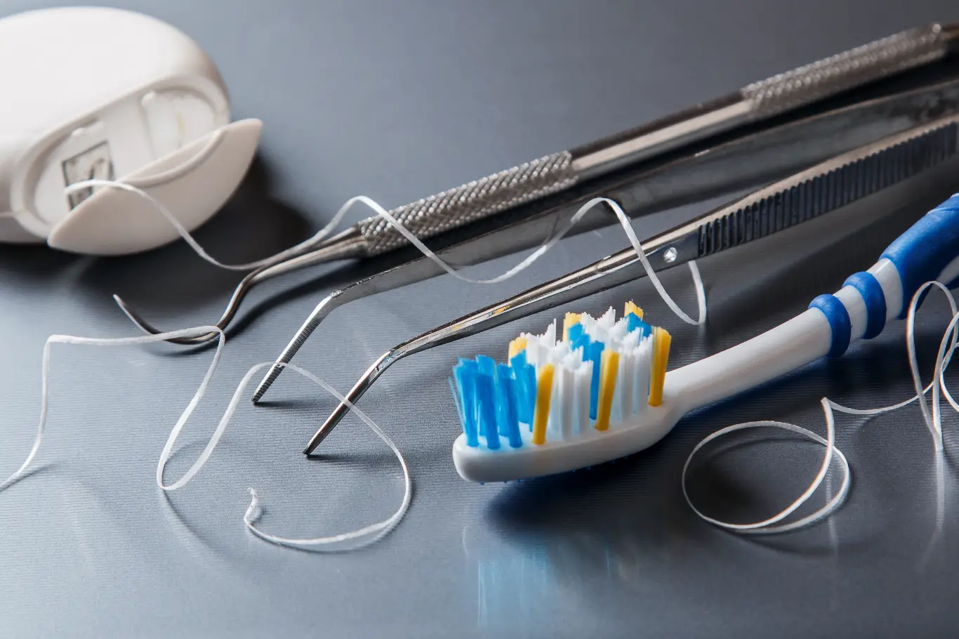 Different tools for dental care including floss and toothbrush.